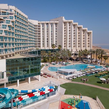 Leonardo Club Hotel Dead Sea Neve Zohar Exterior foto The image shows a large hotel complex alongside a pool area. The hotel features modern architecture with multiple levels and numerous balconies. In front of the hotel, there is a recreational area with a swimming pool, water slides, and lounging chai
